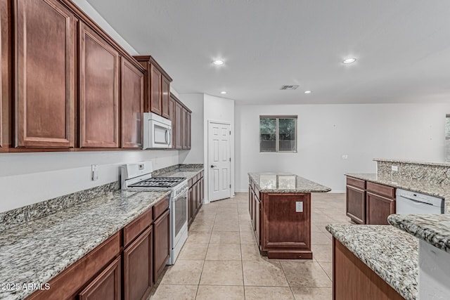 kitchen with light tile patterned flooring, visible vents, recessed lighting, white appliances, and light stone countertops