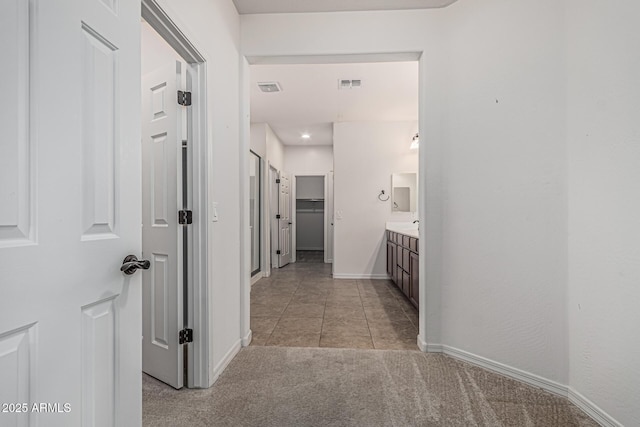 hallway featuring visible vents, baseboards, light carpet, and light tile patterned floors