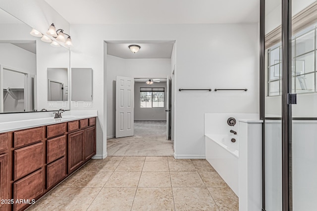 full bath featuring a garden tub, a ceiling fan, vanity, and baseboards