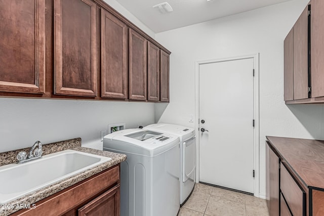 clothes washing area with cabinet space, washing machine and dryer, light tile patterned floors, and a sink