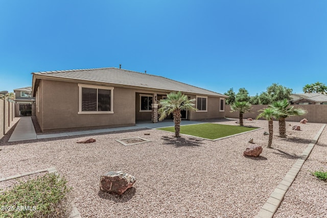 back of house with stucco siding, a tile roof, a patio area, and a fenced backyard