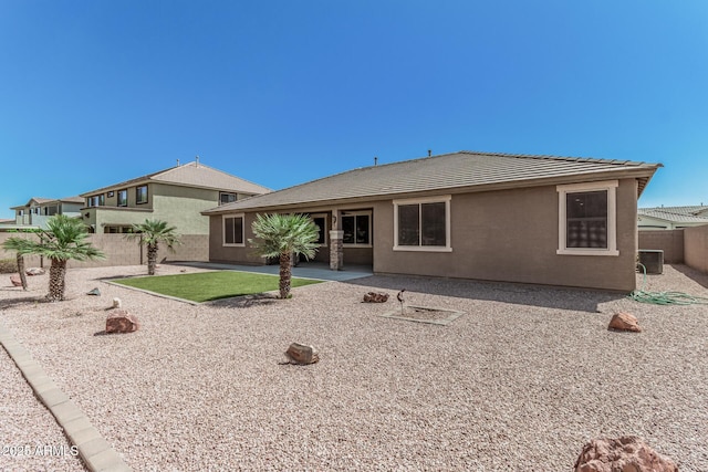 rear view of property with fence private yard, a patio, a tiled roof, and stucco siding
