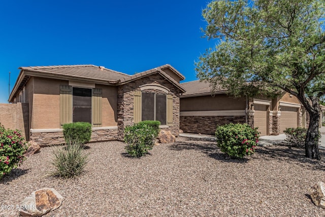 ranch-style home featuring an attached garage, stone siding, a tiled roof, and stucco siding