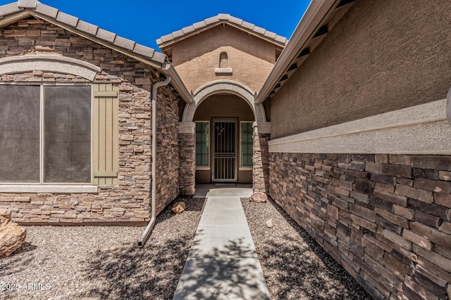 doorway to property featuring stone siding and stucco siding