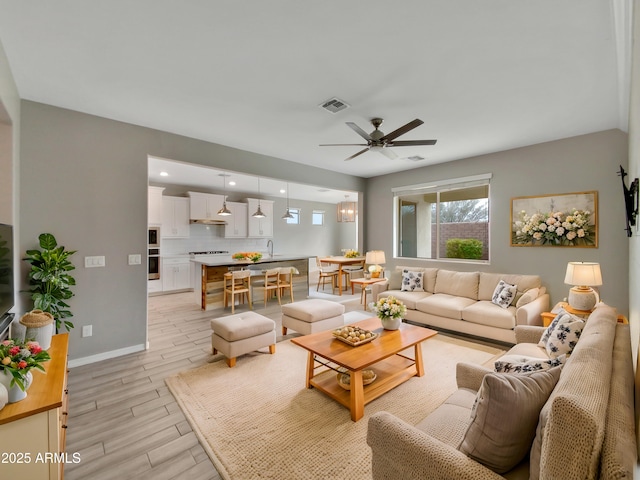 living room with ceiling fan, sink, and light hardwood / wood-style flooring