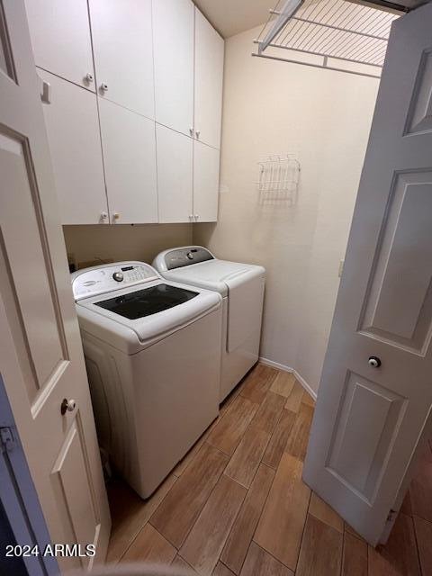 washroom with independent washer and dryer, cabinets, and light wood-type flooring