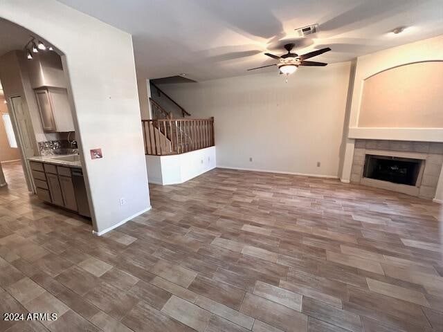 unfurnished living room featuring ceiling fan and a tiled fireplace