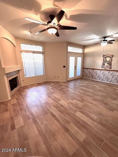 unfurnished living room featuring ceiling fan, wood-type flooring, and french doors