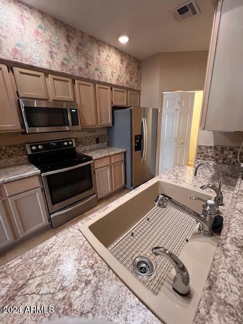 kitchen featuring light stone countertops, appliances with stainless steel finishes, and sink