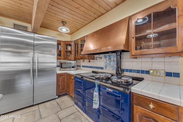 kitchen with brown cabinets, island exhaust hood, appliances with stainless steel finishes, and decorative backsplash