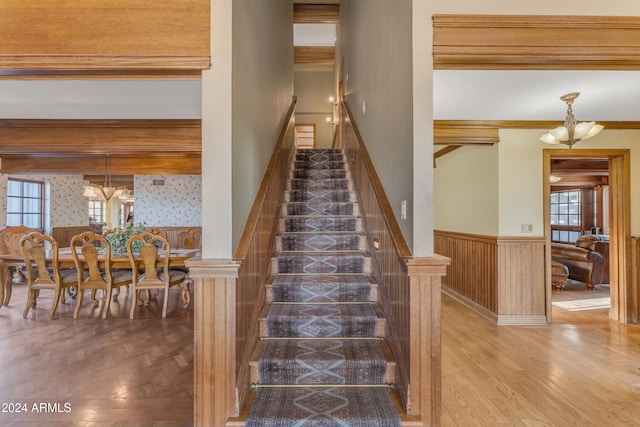 staircase featuring parquet floors, a notable chandelier, and wainscoting