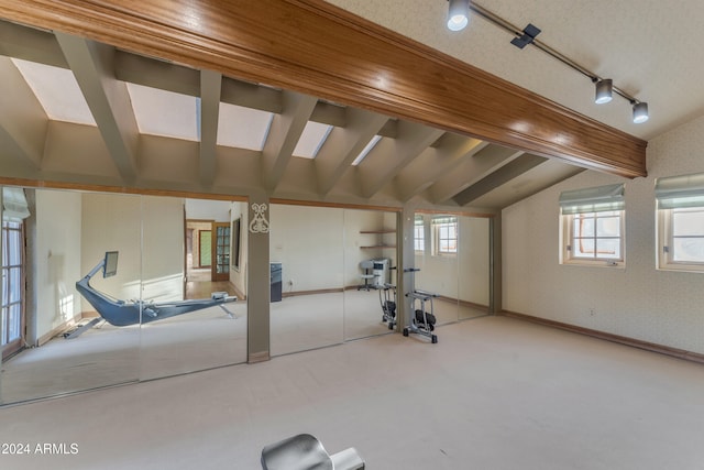 workout room with wallpapered walls, baseboards, vaulted ceiling, and rail lighting