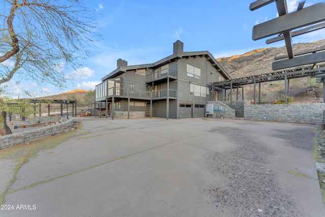 exterior space featuring driveway, a chimney, an attached garage, and a mountain view