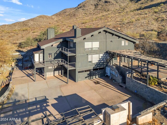 rear view of property with a balcony, a garage, a mountain view, and concrete driveway