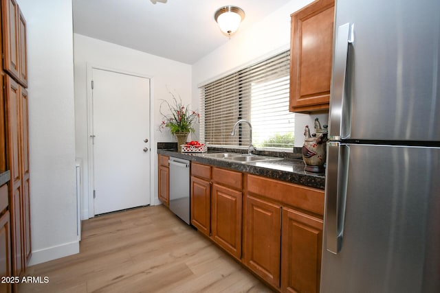 5122 E Shea Blvd Unit 1043, Scottsdale, AZ 85254 - kitchen with stainless steel appliances, a sink, light wood-style flooring, dark countertops, and brown cabinetry