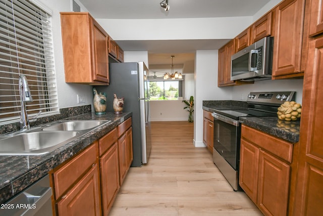 5122 E Shea Blvd Unit 1043, Scottsdale, AZ 85254 - kitchen with stainless steel appliances, a sink, light wood-style flooring, a chandelier, and dark countertops