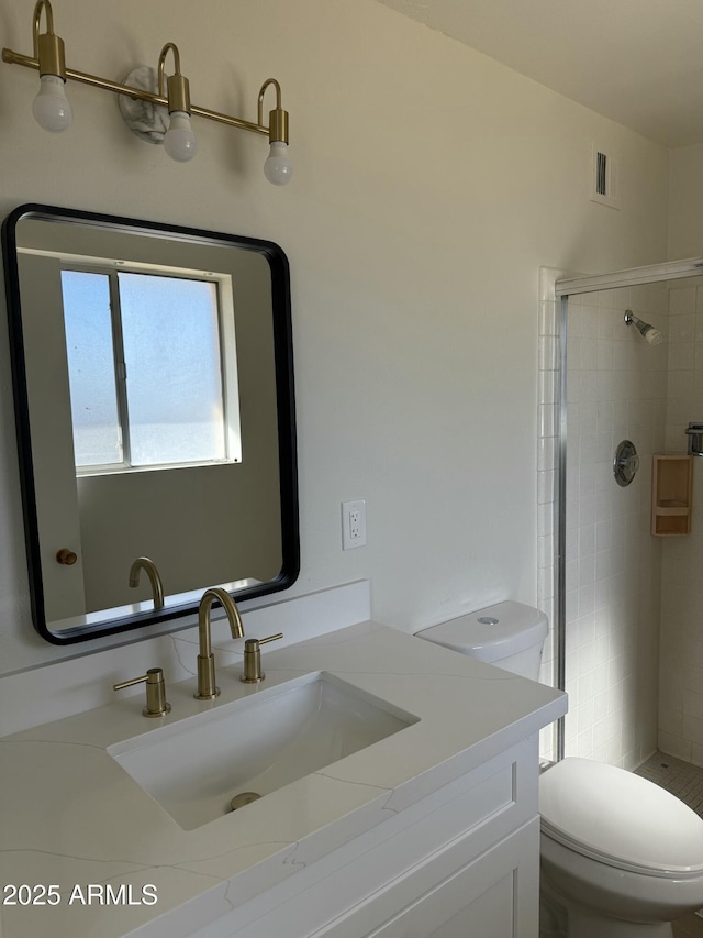 bathroom with vanity, toilet, and tiled shower