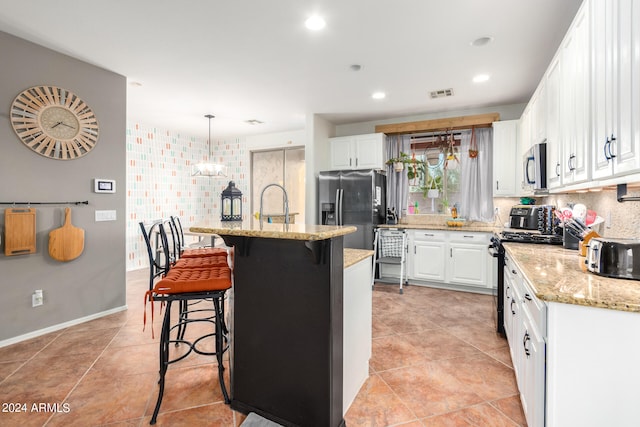 kitchen with stainless steel appliances, a breakfast bar, visible vents, white cabinets, and backsplash