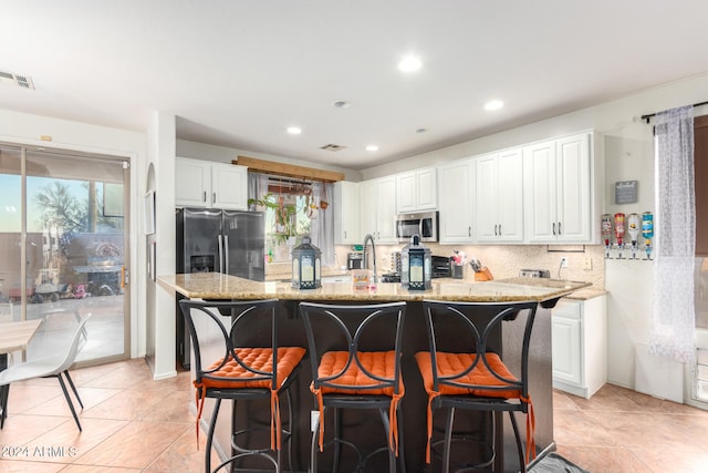 kitchen with appliances with stainless steel finishes, white cabinets, visible vents, and backsplash