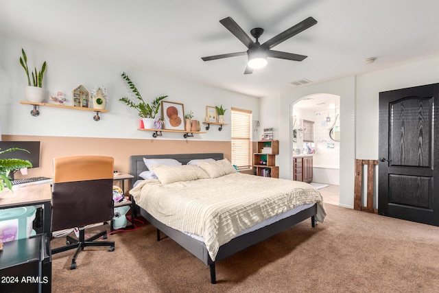 carpeted bedroom featuring ensuite bath, visible vents, arched walkways, and a ceiling fan