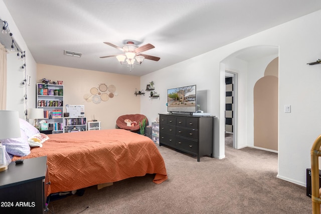 carpeted bedroom featuring arched walkways, ceiling fan, visible vents, and baseboards