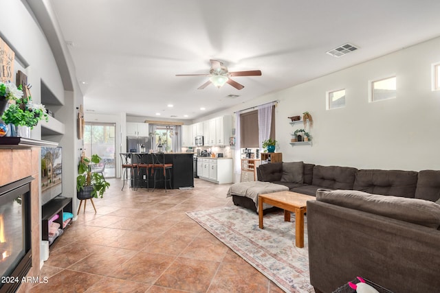 living area featuring beverage cooler, visible vents, a ceiling fan, a tiled fireplace, and recessed lighting