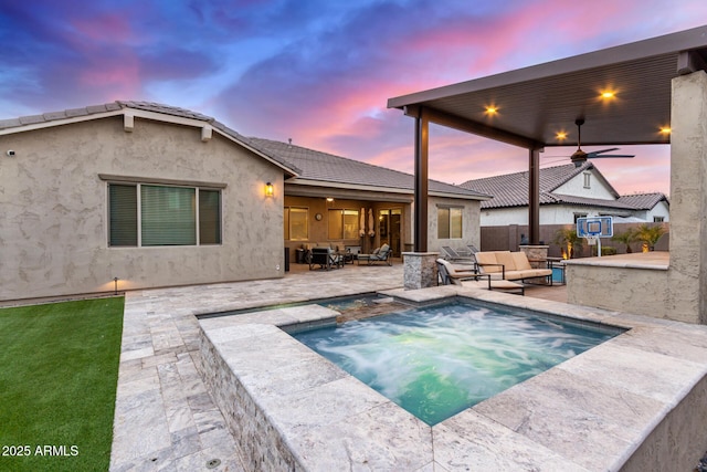 pool at dusk featuring a jacuzzi, a patio area, outdoor lounge area, and ceiling fan