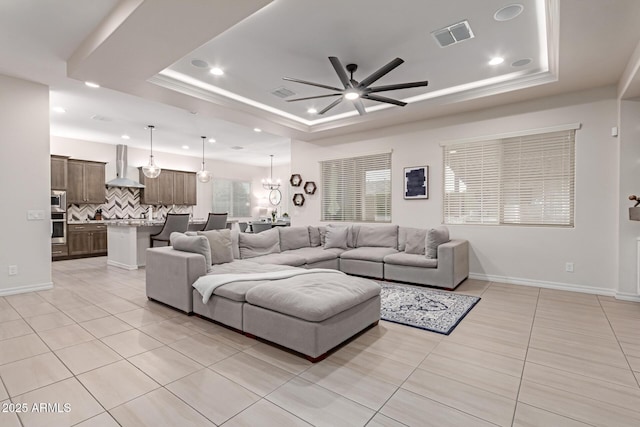 tiled living room featuring a raised ceiling and ceiling fan