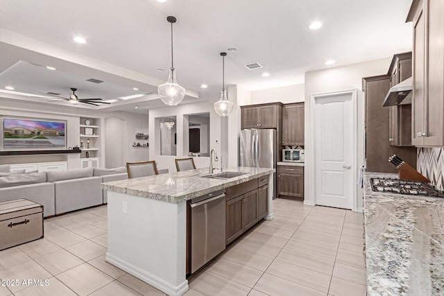 kitchen featuring a kitchen island with sink, sink, light tile patterned floors, and appliances with stainless steel finishes