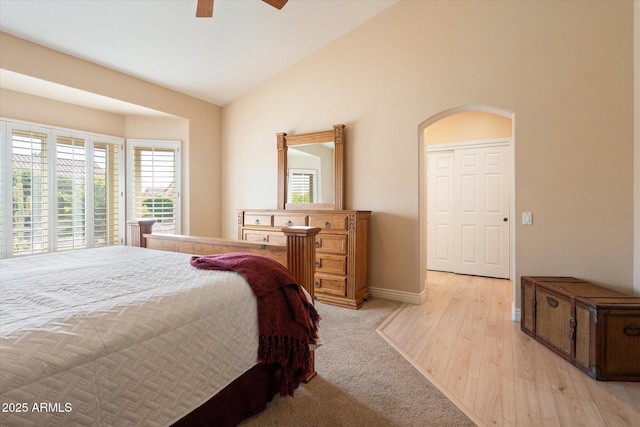 bedroom featuring arched walkways, a ceiling fan, baseboards, vaulted ceiling, and light wood finished floors