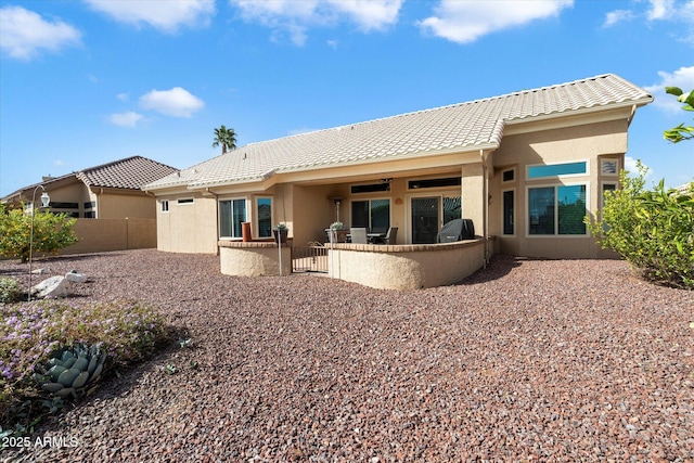 rear view of house with a patio area, fence, a tiled roof, and stucco siding