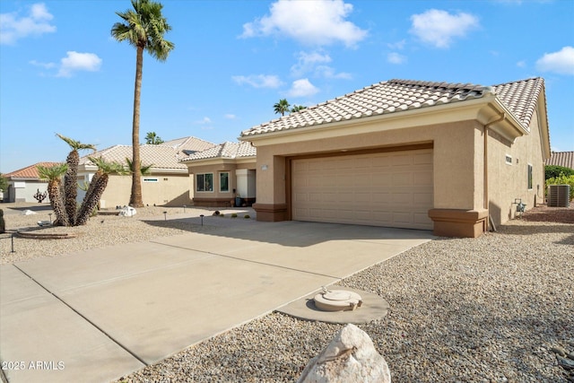 mediterranean / spanish-style home with a tile roof, central AC, concrete driveway, and stucco siding