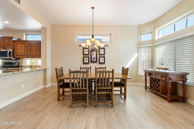 dining room featuring baseboards, a notable chandelier, and light wood-style floors