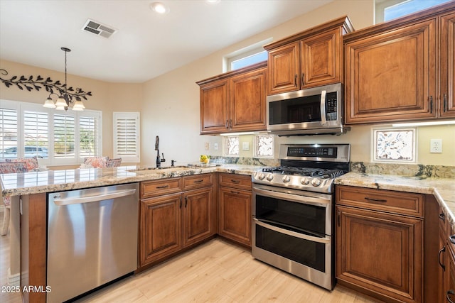 kitchen featuring stainless steel appliances, brown cabinets, visible vents, and a sink