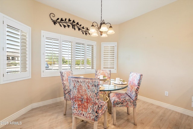 dining space featuring a notable chandelier, light wood-style flooring, and baseboards