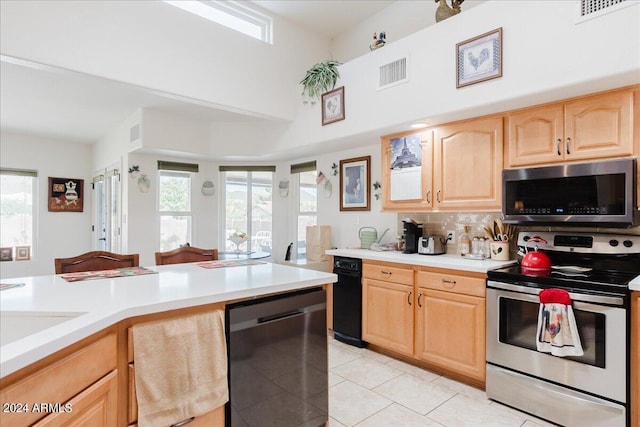 kitchen with light brown cabinets, backsplash, light tile patterned floors, a towering ceiling, and appliances with stainless steel finishes