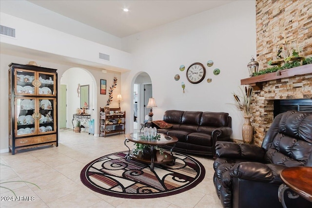 living room featuring a stone fireplace and light tile patterned flooring