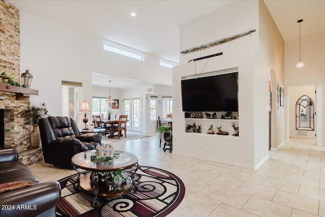 living room with light tile patterned floors, a towering ceiling, and a stone fireplace