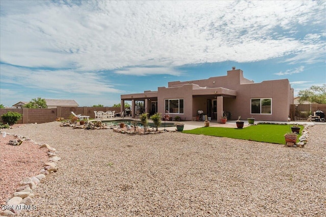 back of property with a fenced in pool and a patio area