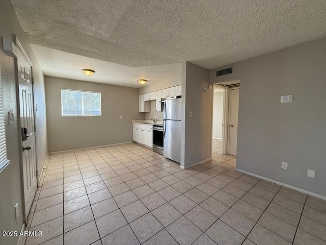 kitchen featuring light tile patterned floors, stainless steel appliances, white cabinets, and a sink