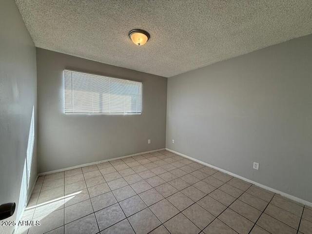 unfurnished room with baseboards, a textured ceiling, and light tile patterned flooring