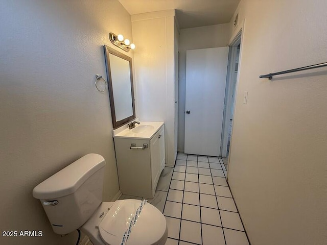 bathroom with toilet, vanity, and tile patterned flooring