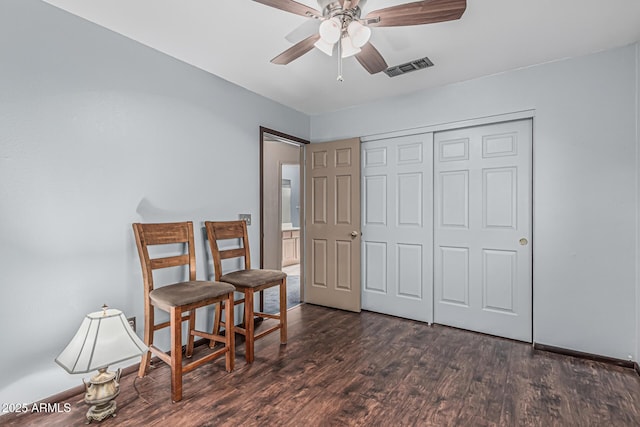 living area with visible vents, dark wood finished floors, and ceiling fan