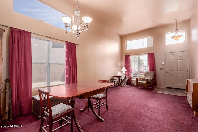 carpeted dining area with a high ceiling, an inviting chandelier, and baseboards
