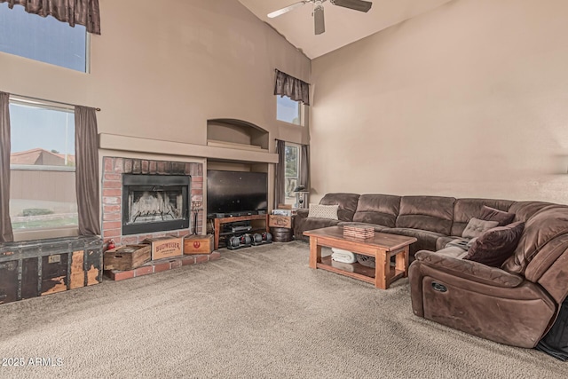 carpeted living room with high vaulted ceiling, a healthy amount of sunlight, ceiling fan, and a fireplace