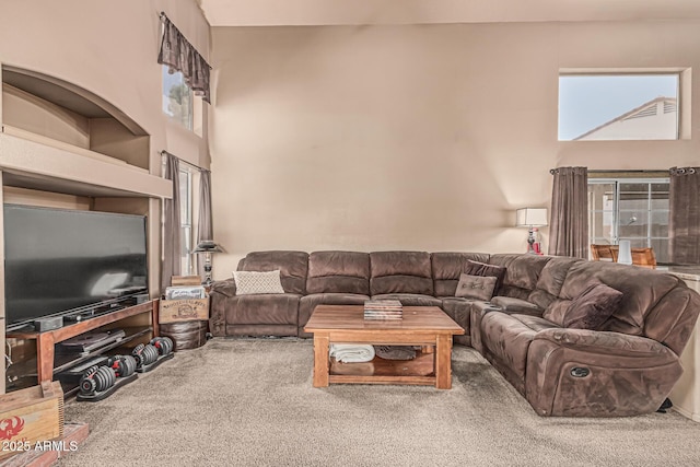carpeted living room featuring a healthy amount of sunlight and a high ceiling
