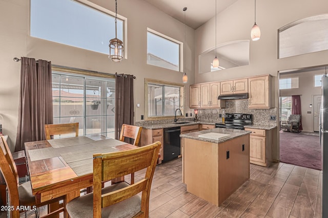 kitchen featuring a kitchen island, light brown cabinets, a high ceiling, a sink, and black appliances