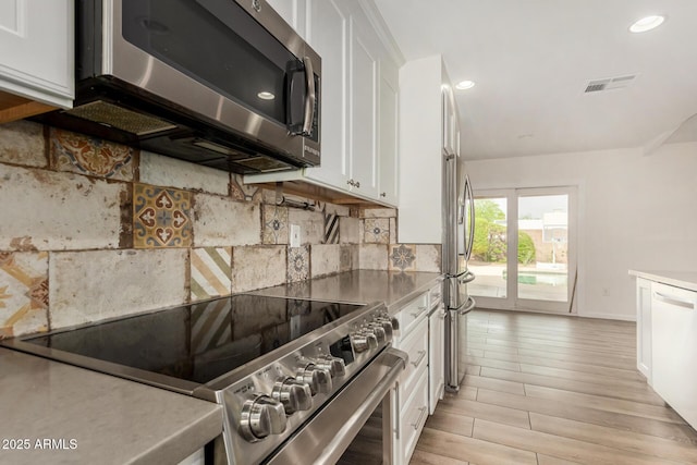 kitchen featuring decorative backsplash, visible vents, appliances with stainless steel finishes, white cabinets, and recessed lighting