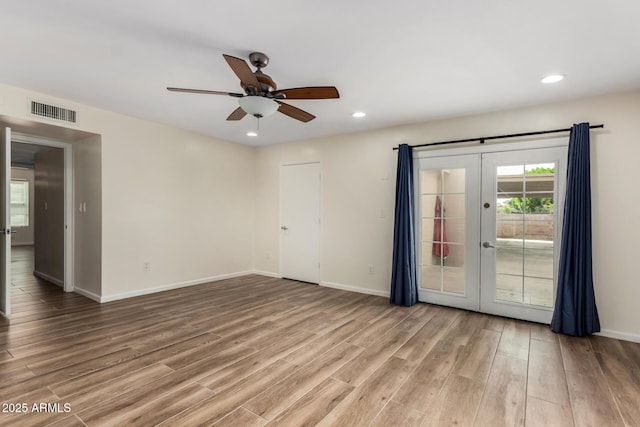 empty room with light wood-style floors, plenty of natural light, french doors, and visible vents