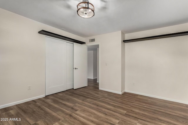 unfurnished bedroom featuring visible vents, baseboards, and wood finished floors